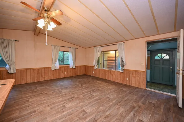 a view of empty room with wooden floor and fan
