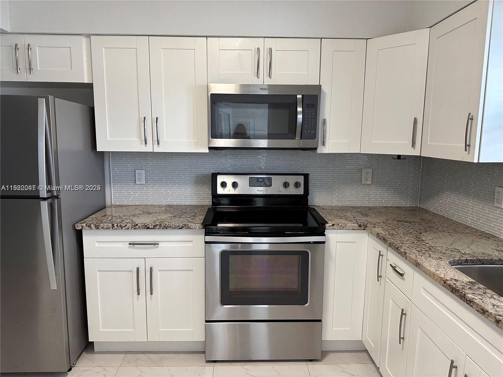 141 Northeast 10th Avenue, Unit 18B Hallandale Beach, FL 33009 - Photo 2 of 15 a kitchen with granite countertop white cabinets and stainless steel appliances
