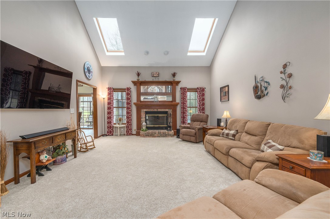 44565 Stang Road Elyria, OH 44035 - Photo 15 of 50 Living room with vaulted cathedral ceiling, dual Skylights, a brick fireplace, carpet floors, and plenty of natural woodwork and light