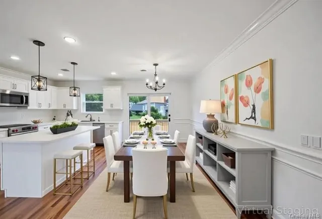 a room with stainless steel appliances kitchen island granite countertop a stove a sink a refrigerator and a dining table with wooden floor