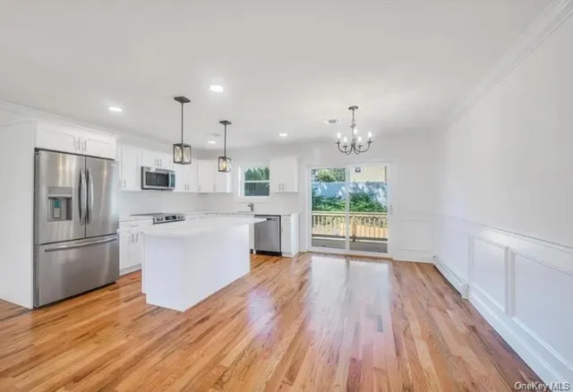 a large kitchen with a wooden floor and stainless steel appliances
