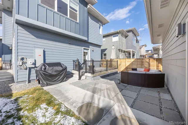 a view of a patio with table and chairs with barbeque and wooden fence