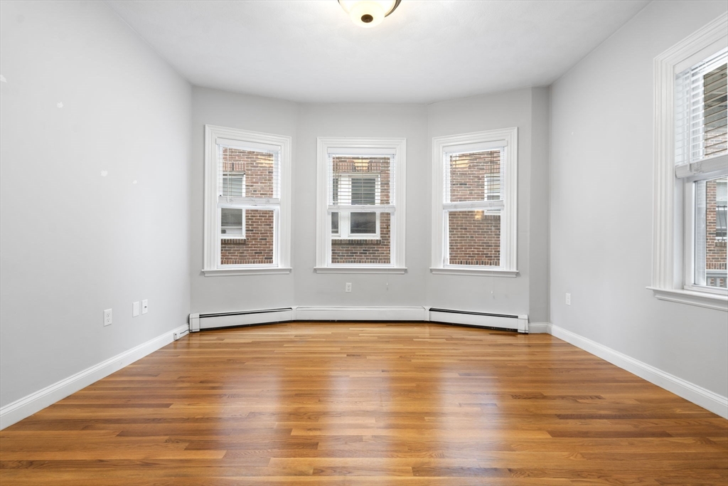 1433 Cambridge Street, Unit 1 Cambridge, MA 02139 - Photo 12 of 14 a view of an empty room with wooden floor and a window