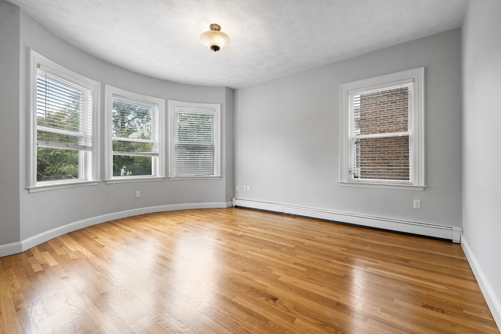 1433 Cambridge Street, Unit 1 Cambridge, MA 02139 - Photo 7 of 14 a view of an empty room with wooden floor and a window