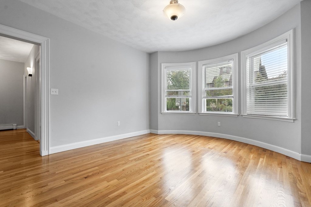 1433 Cambridge Street, Unit 1 Cambridge, MA 02139 - Photo 9 of 14 a view of an empty room with wooden floor and a window