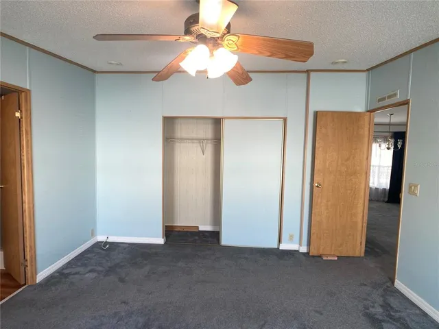 an empty room with closet and a chandelier fan