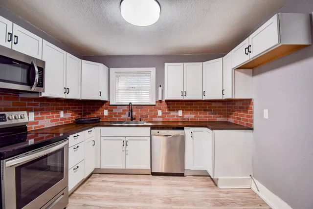 a kitchen with stainless steel appliances granite countertop a stove a sink and a microwave