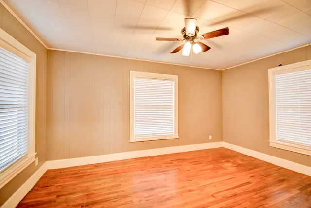 a view of an empty room with wooden floor and a window