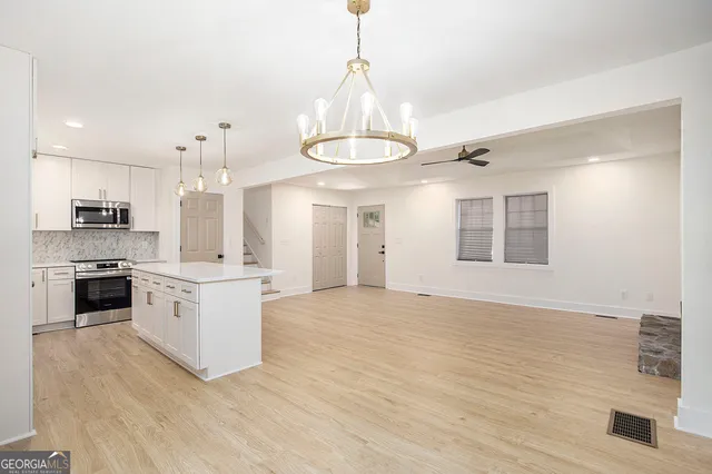 a kitchen with stainless steel appliances granite countertop a stove and white cabinets