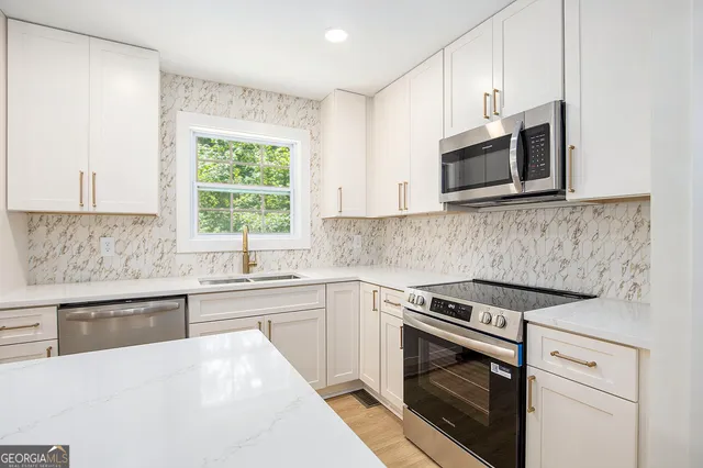 a kitchen with cabinets stainless steel appliances a sink and a window