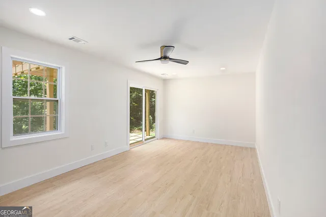 an empty room with a window and a ceiling fan