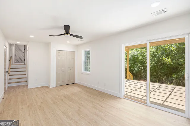 a view of an empty room with wooden floor and a window