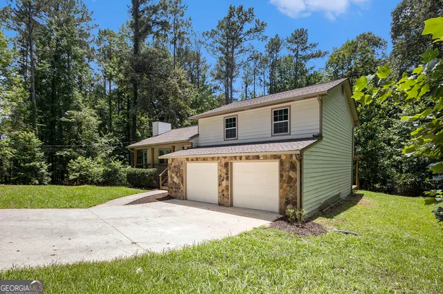 a front view of house with yard and trees in the background