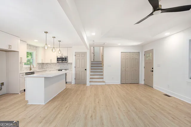 a large white kitchen with white cabinets and wooden floor
