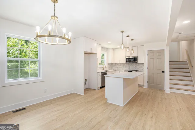 a large kitchen with a center island wooden floor stainless steel appliances and cabinets