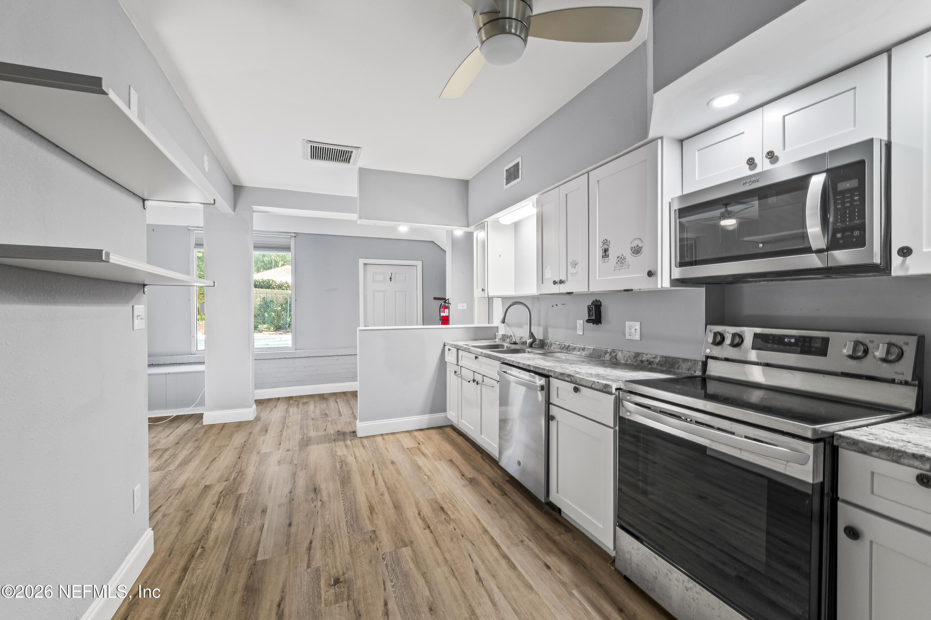 10612 Fort Caroline Road Jacksonville, FL 32225 - Photo 30 of 51 a kitchen with stainless steel appliances a stove a sink cabinets and a wooden floor