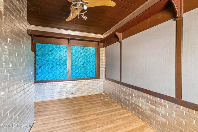 a view of empty room with wooden floor and fan
