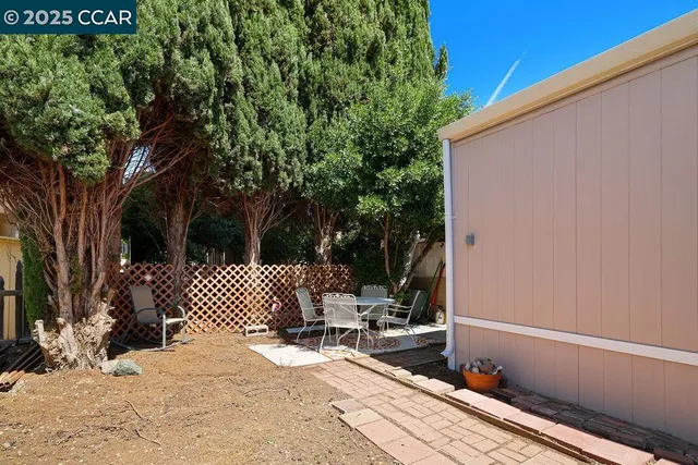 a view of a patio with table and chairs with wooden fence and large trees