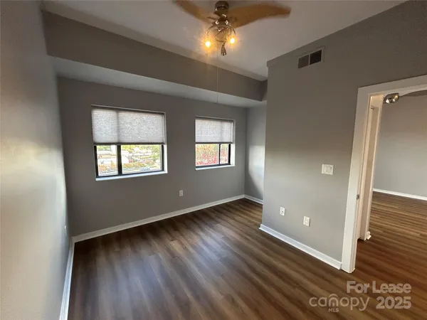 an empty room with wooden floor and windows