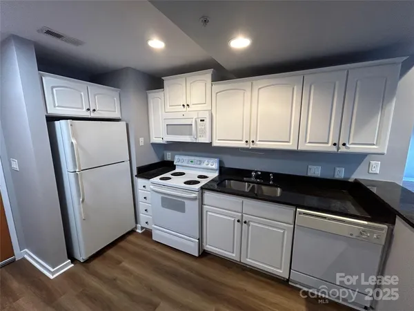 a kitchen with granite countertop white cabinets and white appliances