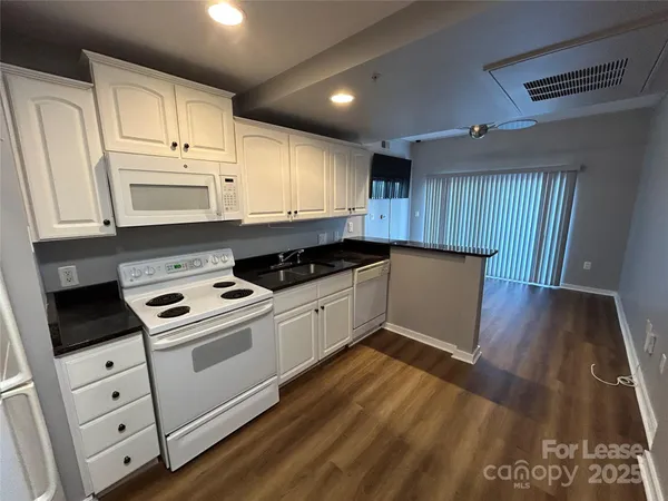 a kitchen with granite countertop wooden cabinets and white appliances