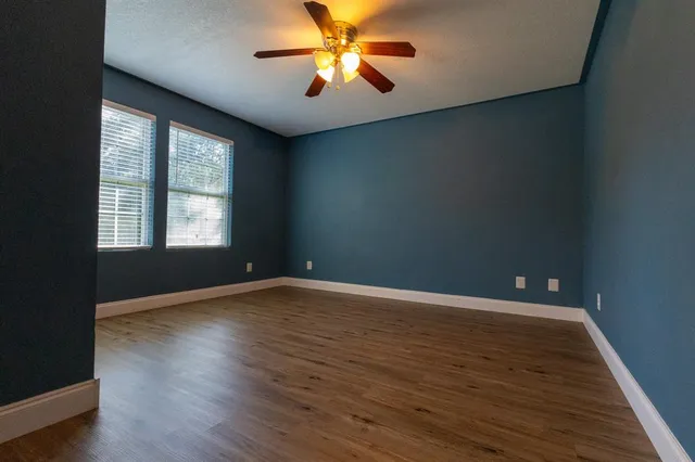 a view of an empty room with window and wooden floor