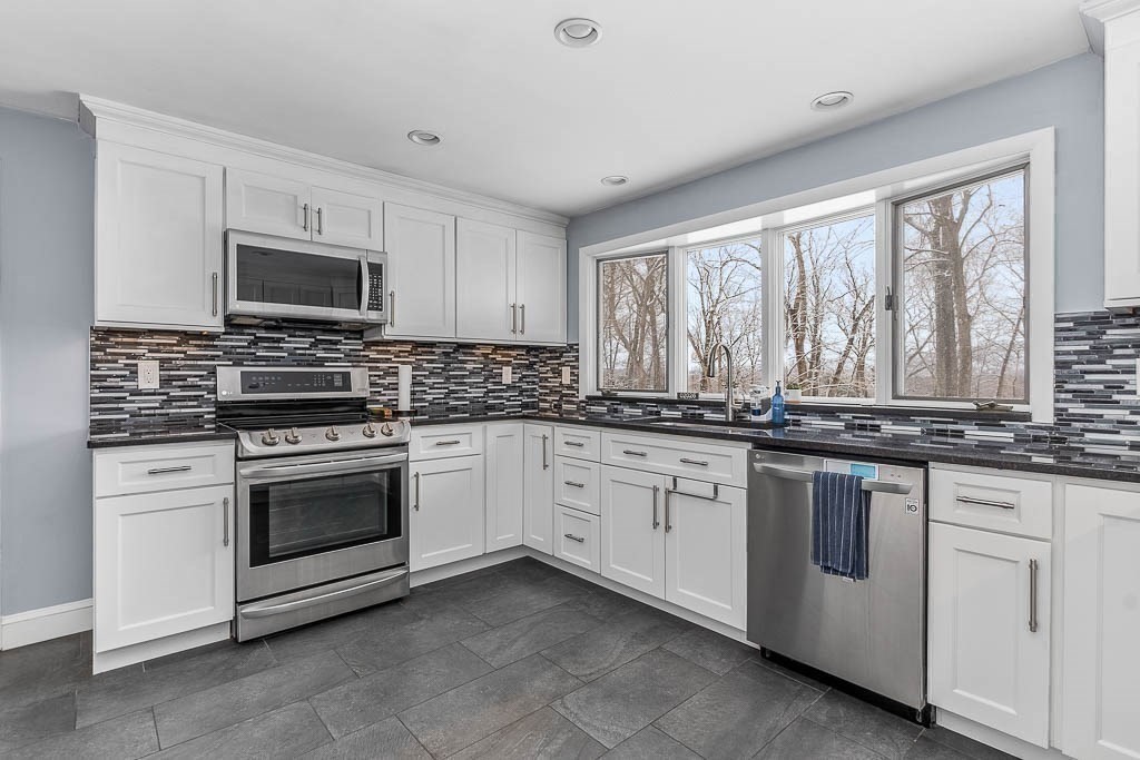 18 Greensboro Road Dedham, MA 02026 - Photo 12 of 39 a kitchen with granite countertop white cabinets sink and stainless steel appliances