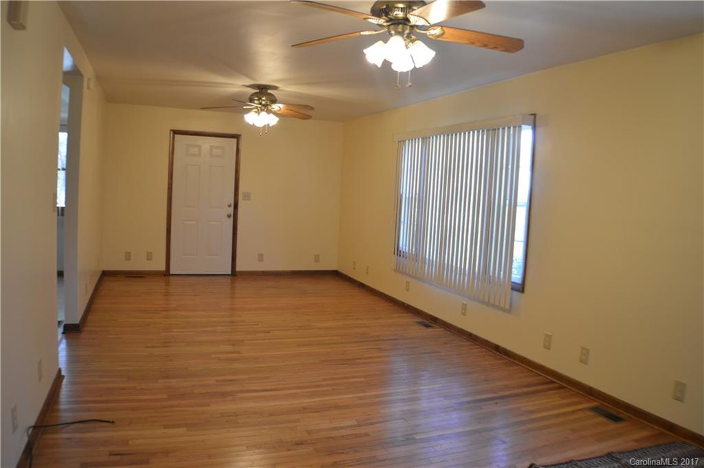 116 Cove Road Rutherfordton, NC 28139 - Photo 8 of 16 an empty room with wooden floor chandelier fan and windows