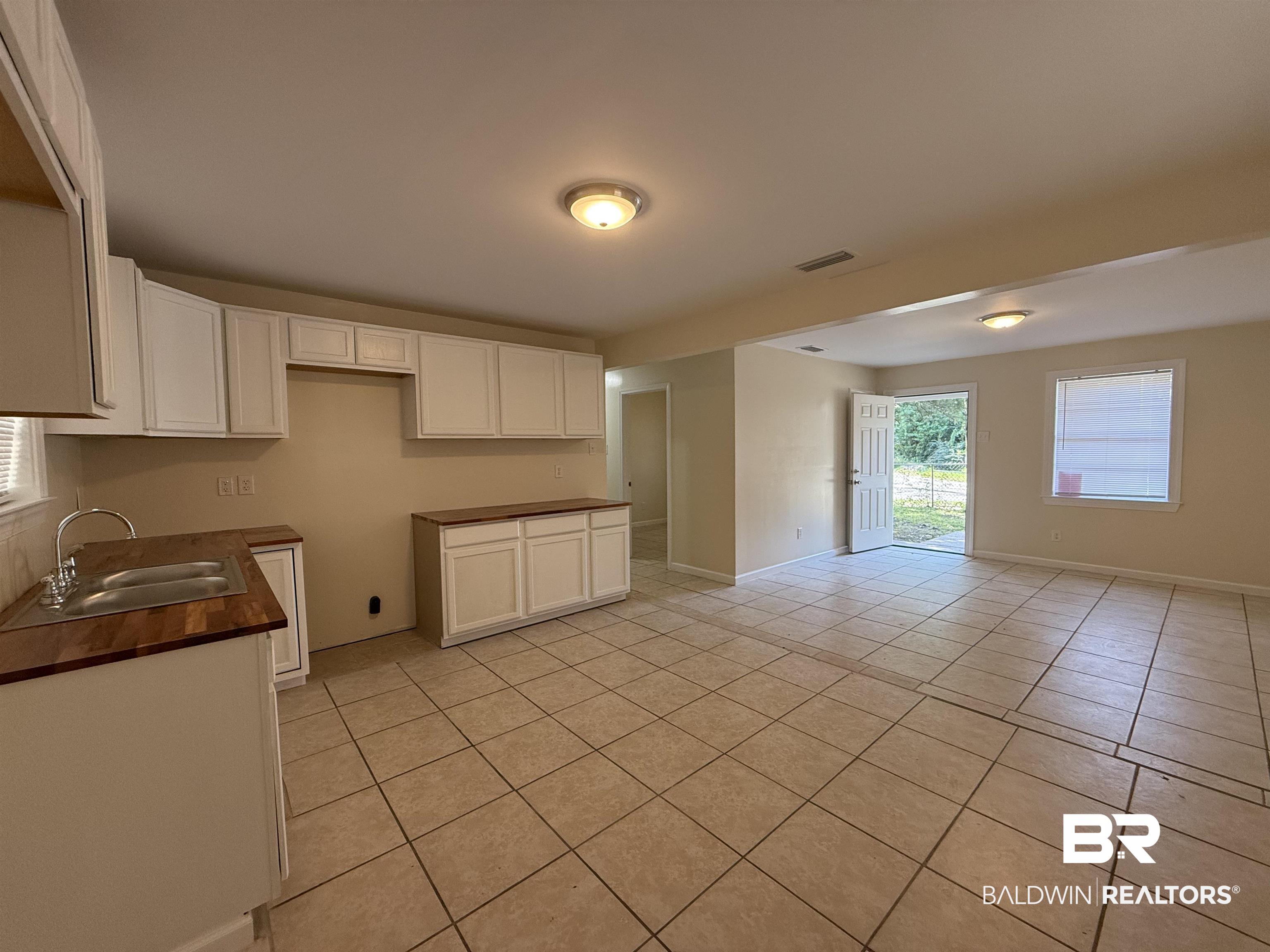 320 E Street Prichard, AL 36610 - Photo 4 of 16 Kitchen featuring light tile patterned flooring, white cabinets, and sink