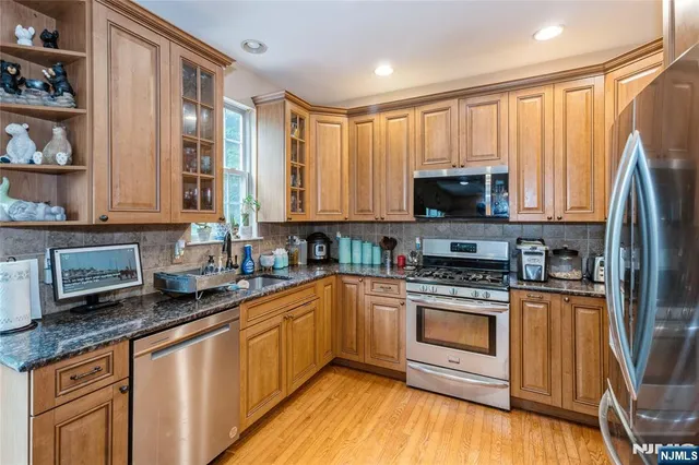 a kitchen with stainless steel appliances granite countertop a stove a sink dishwasher a refrigerator and a microwave