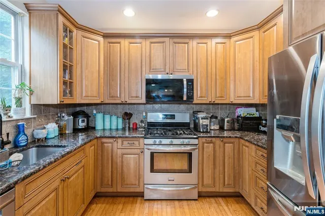 a kitchen with stainless steel appliances granite countertop a stove a sink and a refrigerator