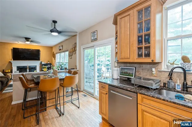 a dining hall with stainless steel appliances granite countertop a stove a sink dishwasher a dining table and chairs with wooden floor