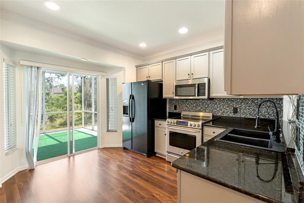 15929 Fishhawk Creek Lane Lithia, FL 33547 - Photo 18 of 25 a kitchen with stainless steel appliances granite countertop a refrigerator oven a sink dishwasher and wooden cabinets with wooden floor