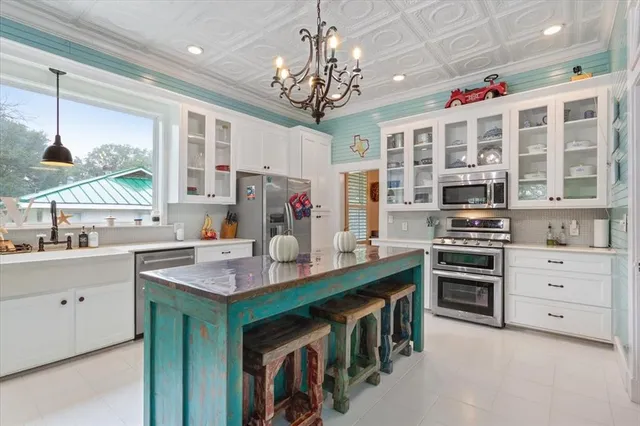 a kitchen that has a lot of white cabinets and stainless steel appliances