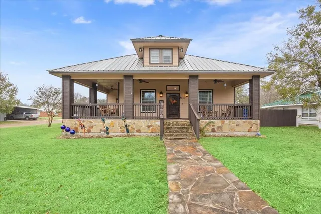 a view of a house with a yard deck and a large tree