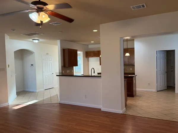 a view of a kitchen with a refrigerator a ceiling fan wooden floor and a kitchen space