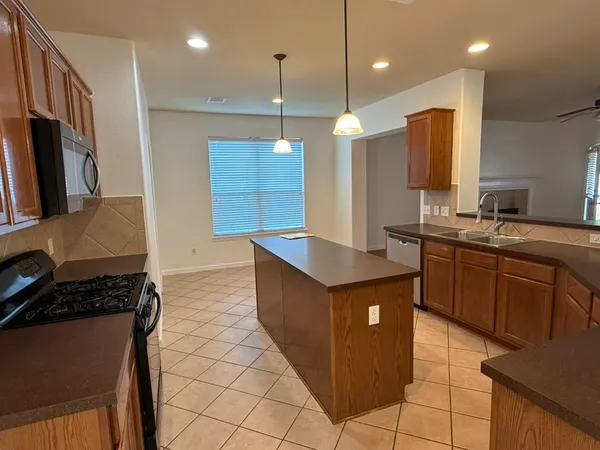 a kitchen with kitchen island granite countertop a sink a counter top space appliances and cabinets