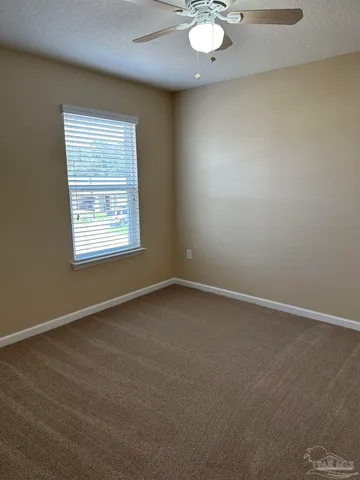 an empty room with a window and ceiling fan