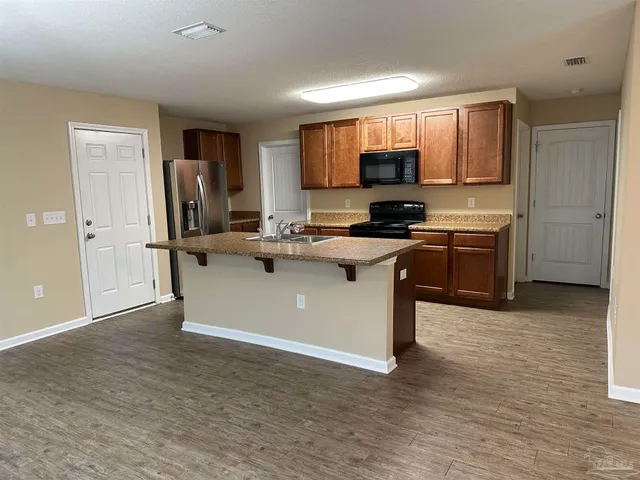 a large open kitchen with a refrigerator a stove top oven a sink and dishwasher