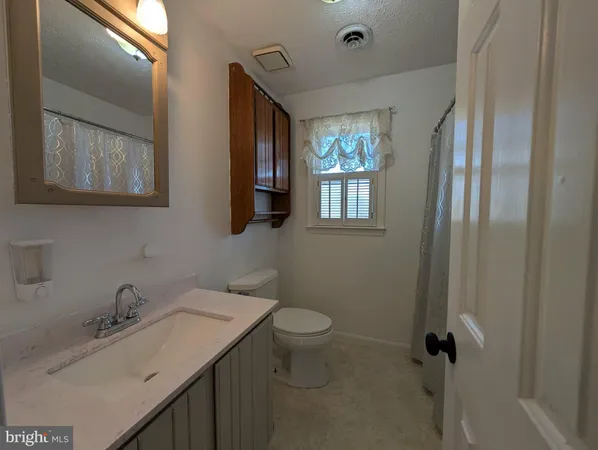 a bathroom with a granite countertop sink toilet and mirror