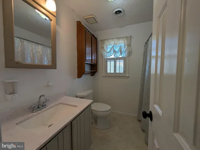 a bathroom with a granite countertop sink toilet and mirror