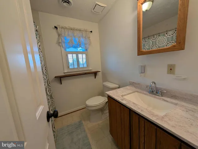 a bathroom with a granite countertop sink mirror vanity and toilet