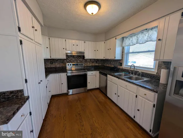 a large kitchen with stainless steel appliances granite countertop a stove a sink and a refrigerator