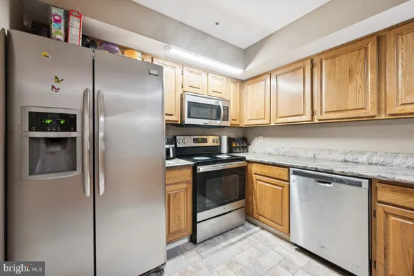 a kitchen with granite countertop a refrigerator stove and microwave