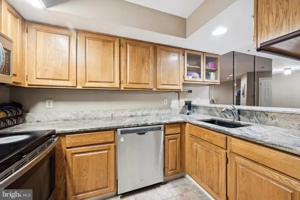 a kitchen with granite countertop stainless steel appliances white cabinets sink and window