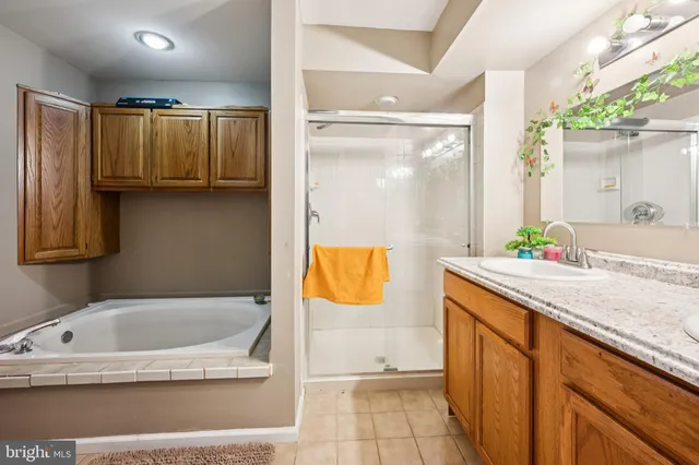 a bathroom with a granite countertop tub sink and mirror