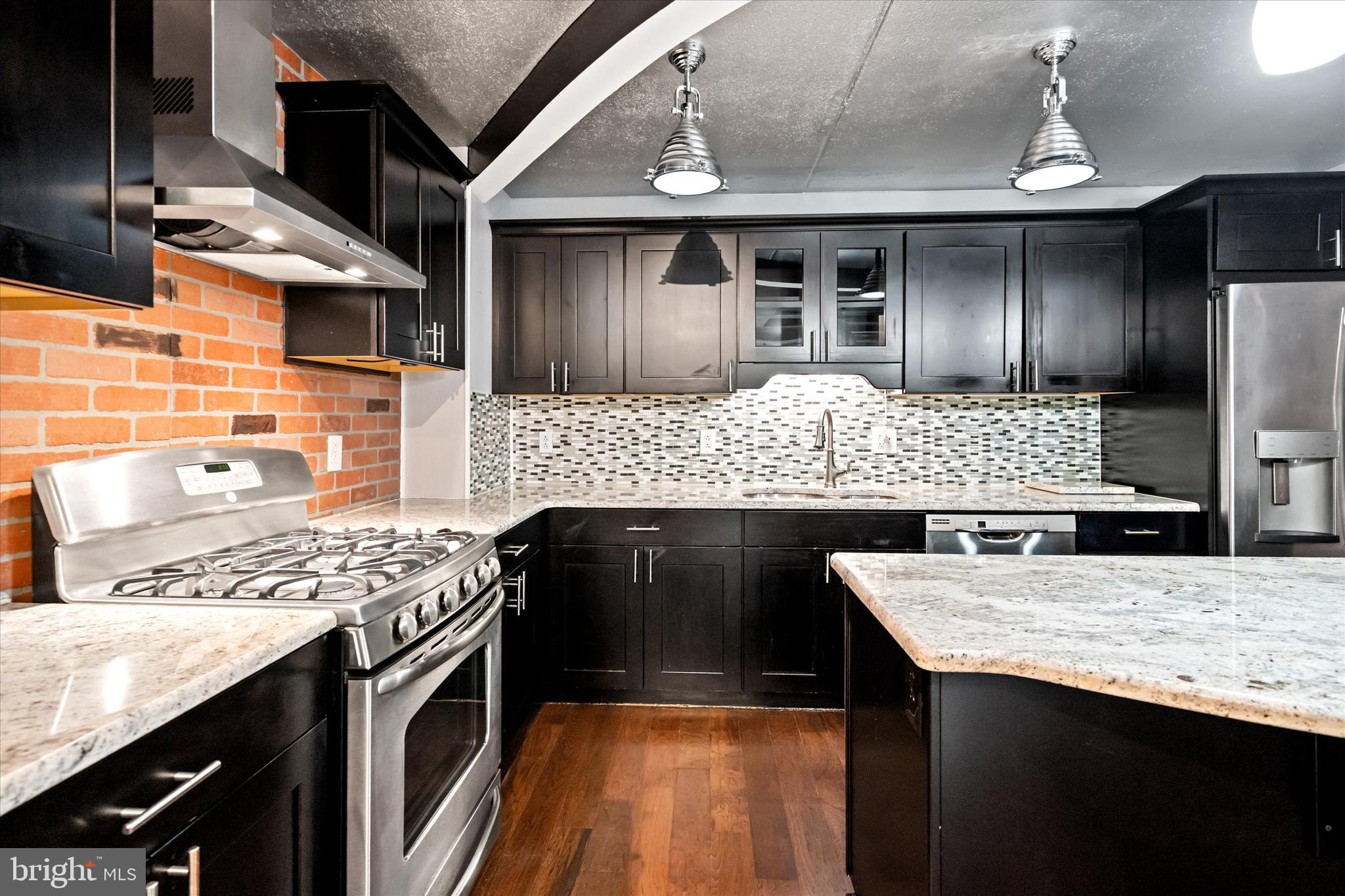 80 Welsh Tract Road, Unit G209 Newark, DE 19713 - Photo 4 of 26 a kitchen with stainless steel appliances kitchen island granite countertop a wooden cabinets and stove