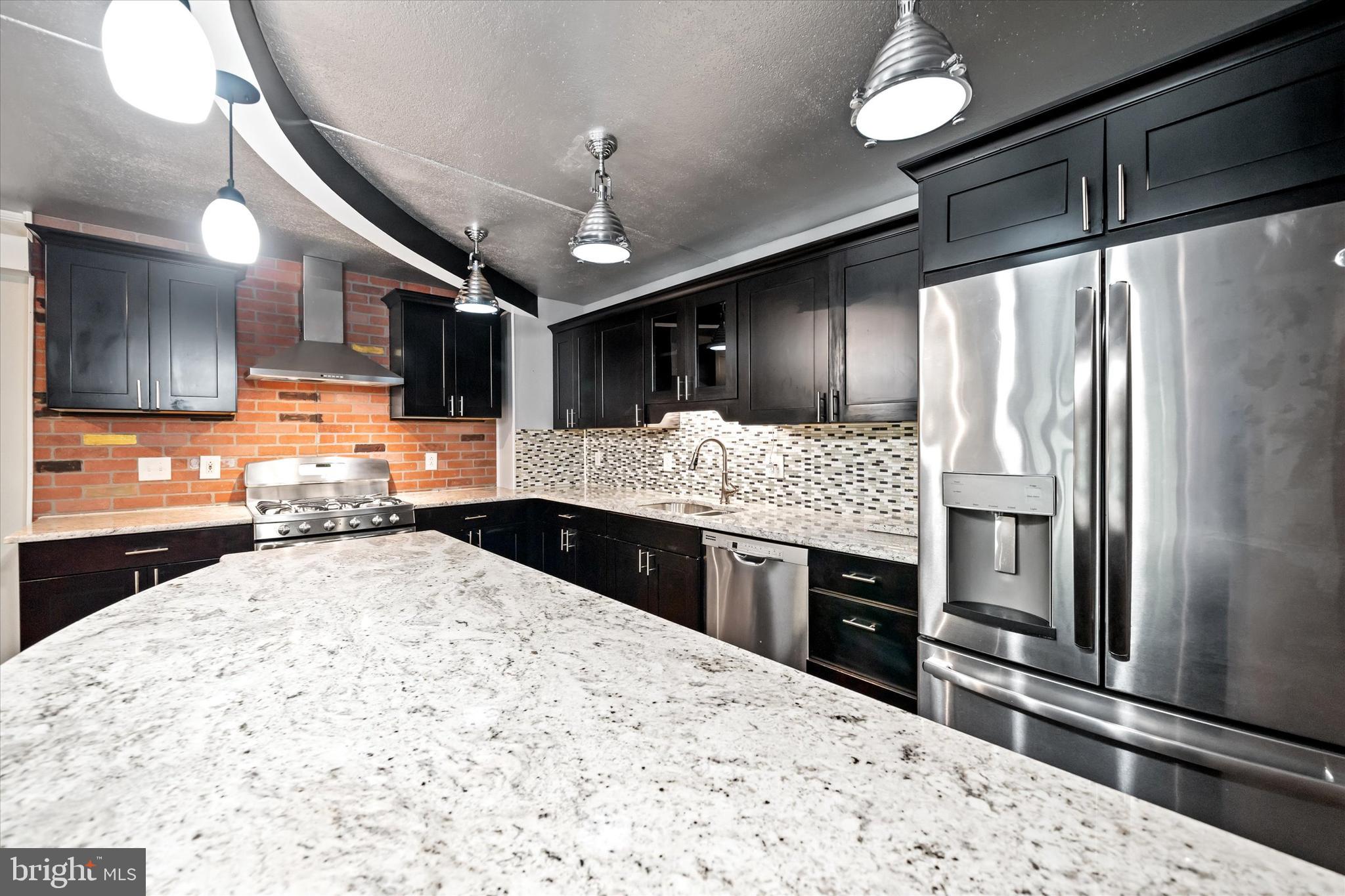80 Welsh Tract Road, Unit G209 Newark, DE 19713 - Photo 5 of 26 a kitchen with stainless steel appliances kitchen island granite countertop a refrigerator oven a sink dishwasher and wooden cabinets with wooden floor