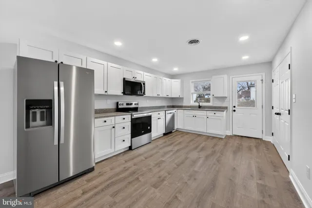 a large kitchen with white cabinets stainless steel appliances and a window