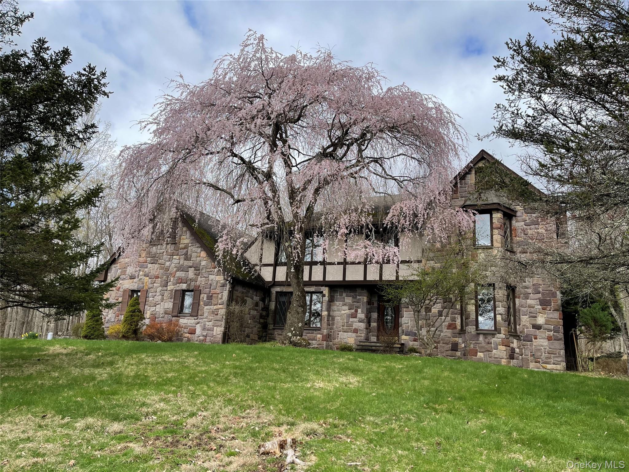 a view of a big house with a big yard and large trees